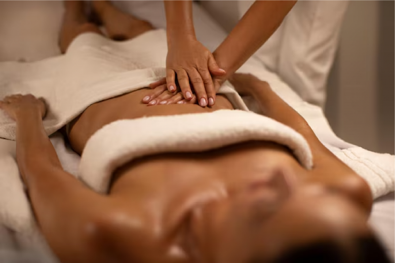 masseur-making-relaxing-massage-stomach-lying-woman-calm-spa-center-interior-professional_726520-1189